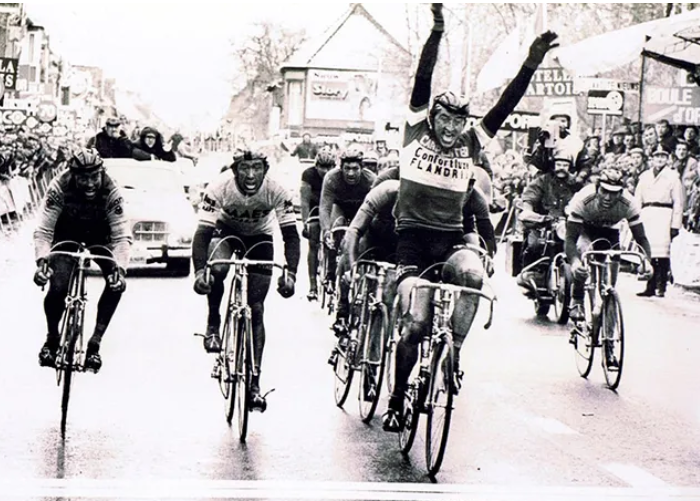 Winning cyclist raising both arms at the finish
